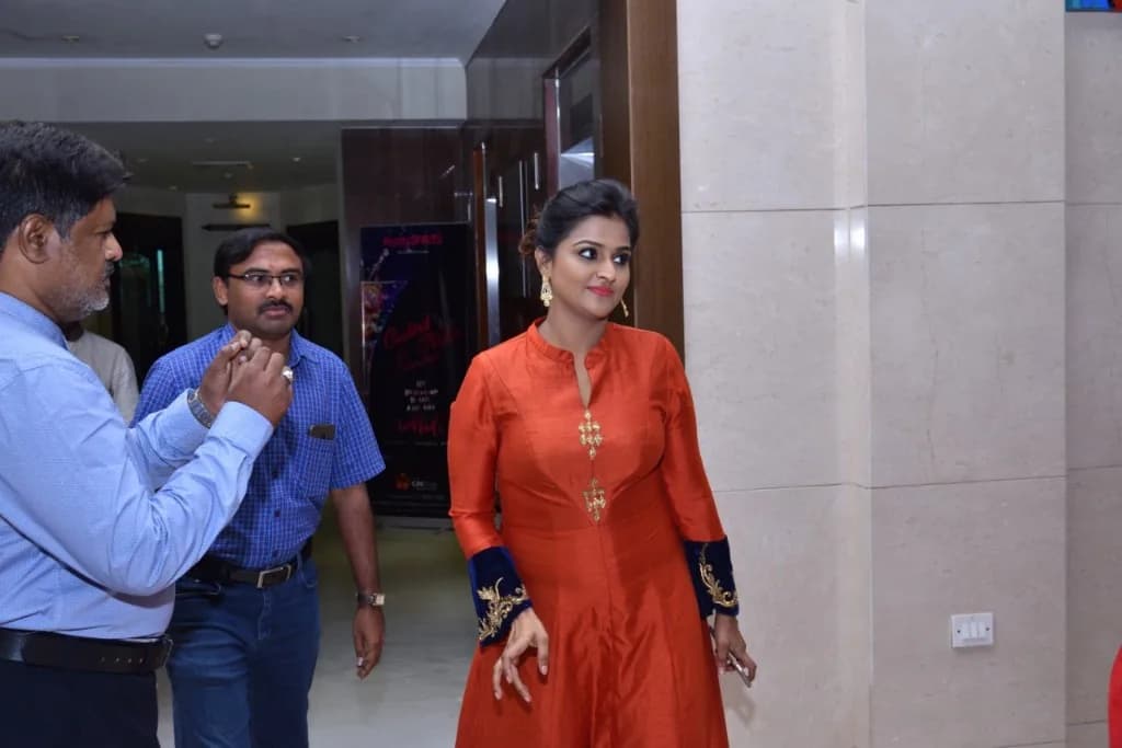 Celebrity guest in traditional attire at an indoor event with AirMedia team members