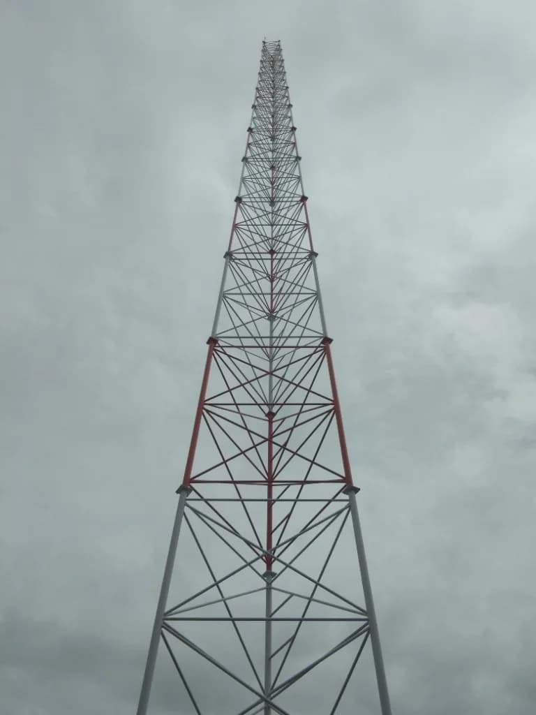 Looking up a red and white community radio broadcast tower structure